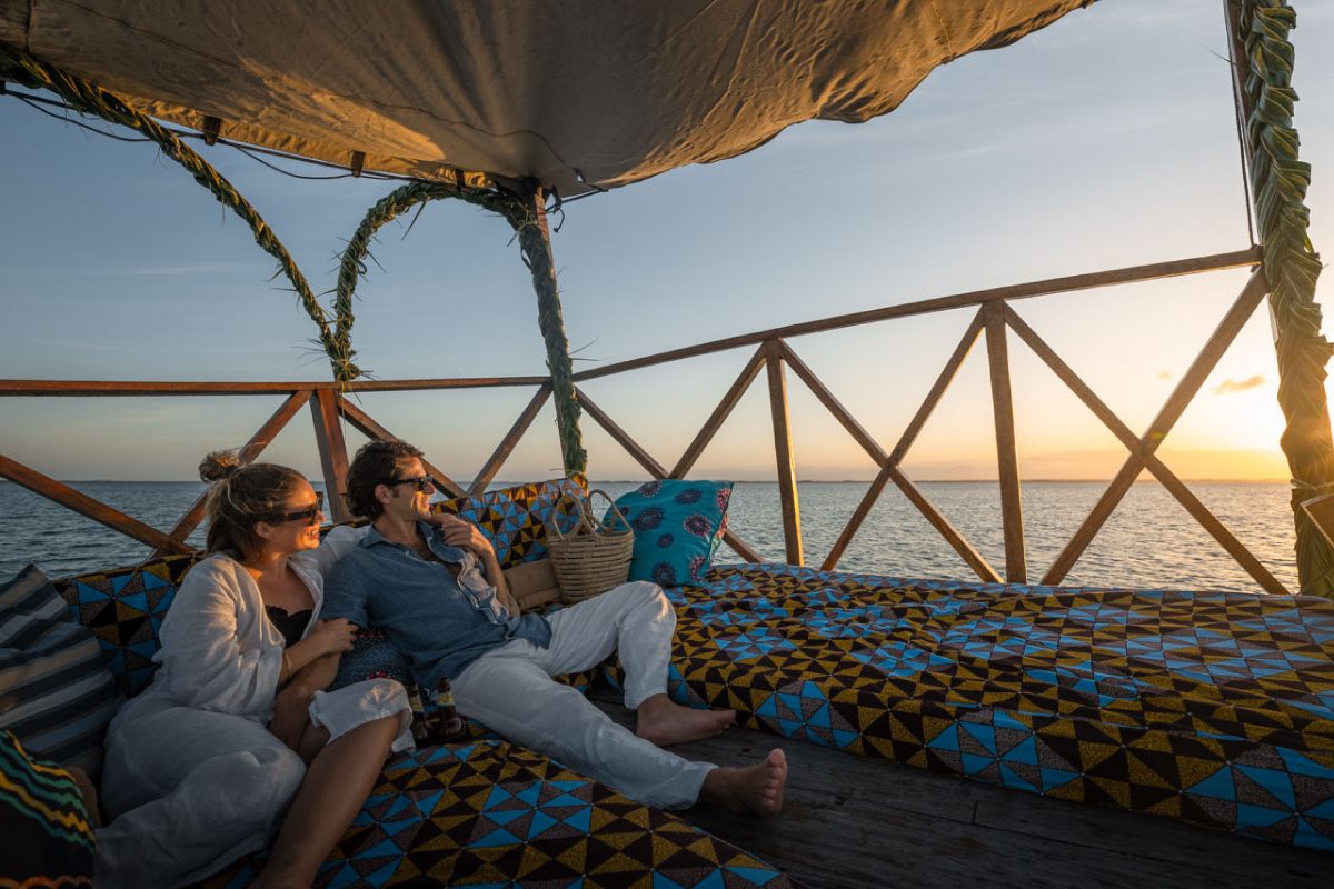 A couple on a daybed watching the sun set over the Indian Ocean